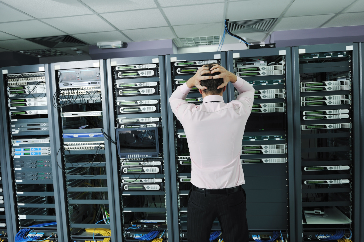 A man in a suit clutching the back of his head as he stares at servers
